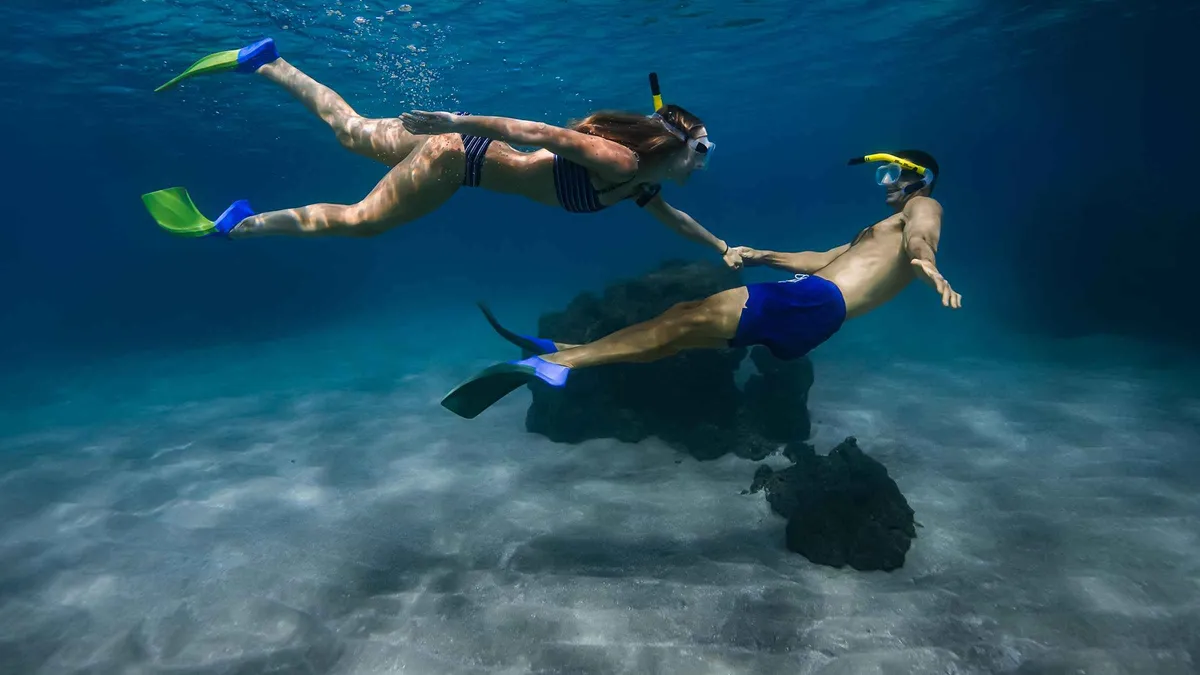A snorkeler photographed underwater beside a Hawaiian green sea turtle at Turtle Town on a Maui snorkel photoshoot trip