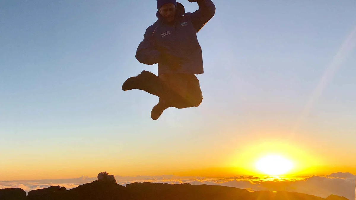 Travelers photographed jumping above the clouds at Haleakala summit at sunset on a Maui photo tour